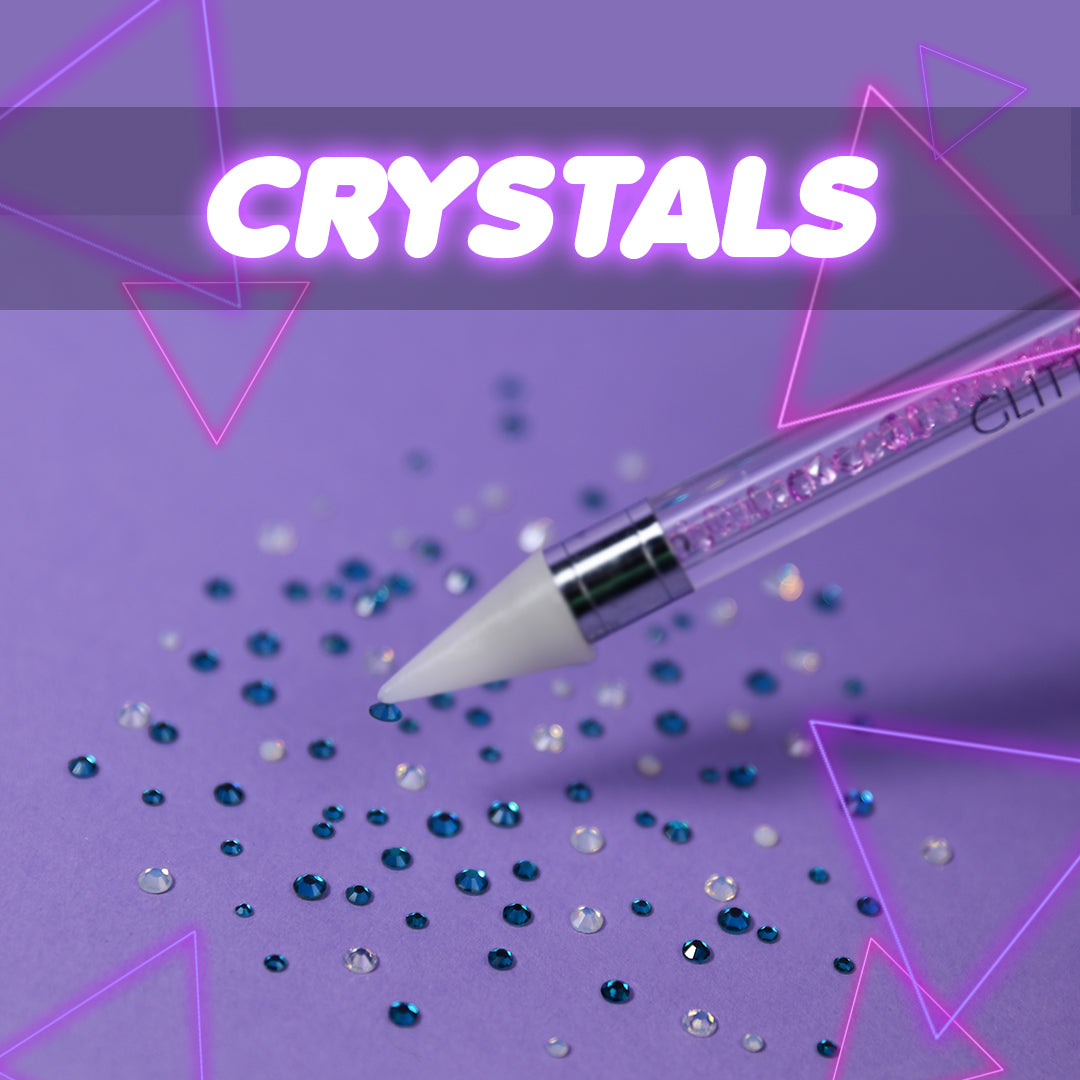 flat back nail art crystals laid out on the design with a wax pen tool picking one up