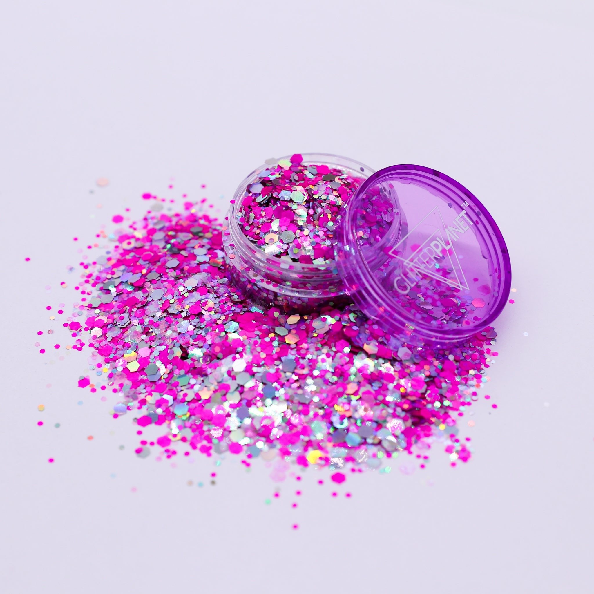 Open container of multicolored glitter with spilled contents on a light white background