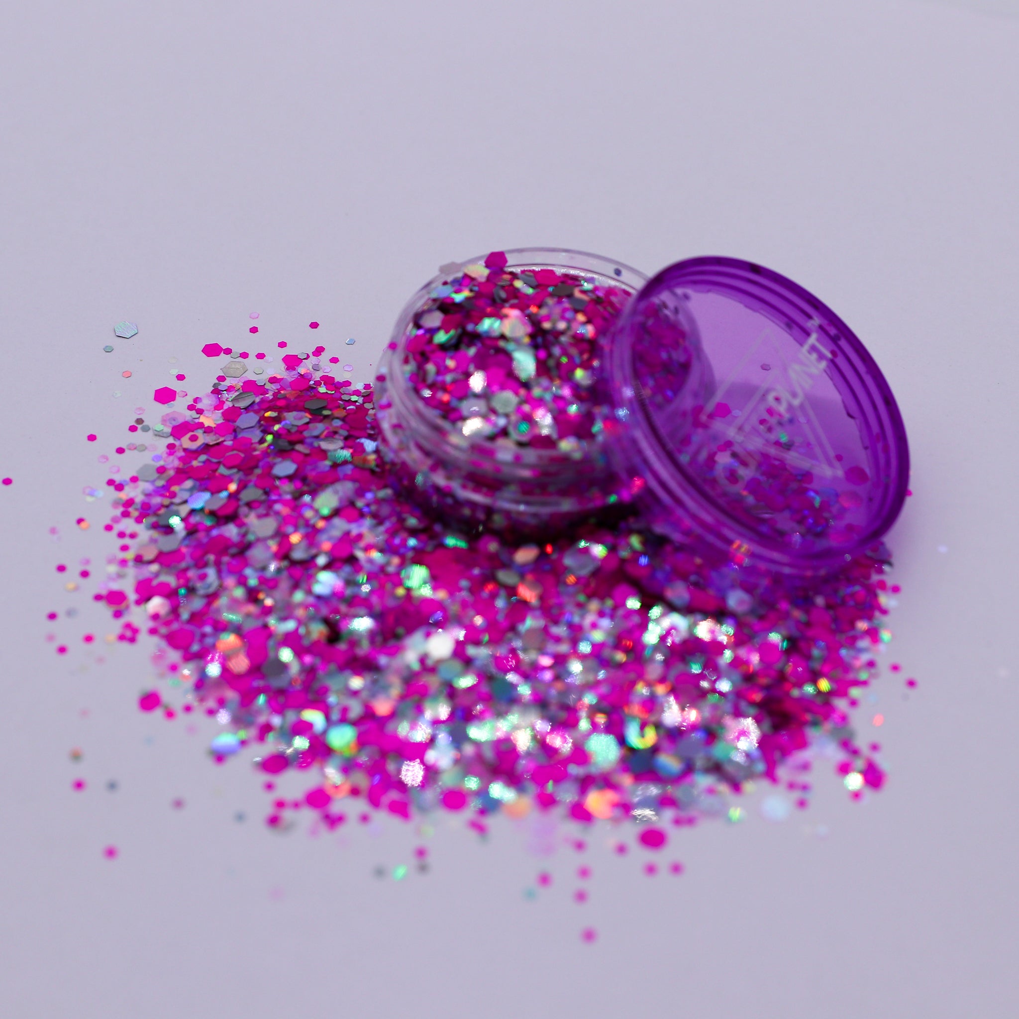 Purple glitter container with spilled glitter on a light gray background