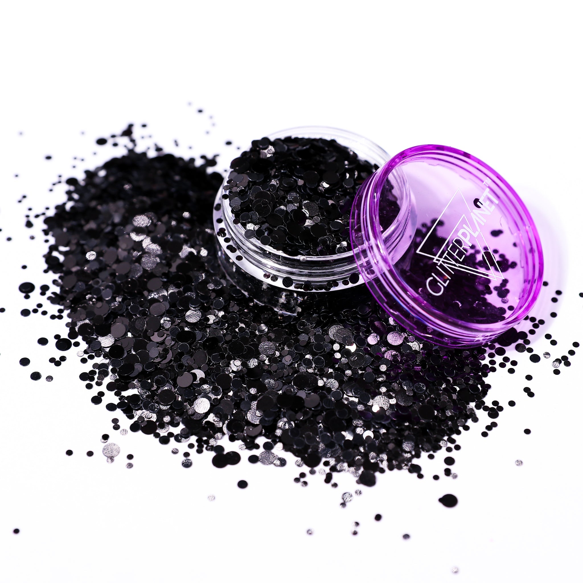Black glitter spilling out of a purple container on a white background
