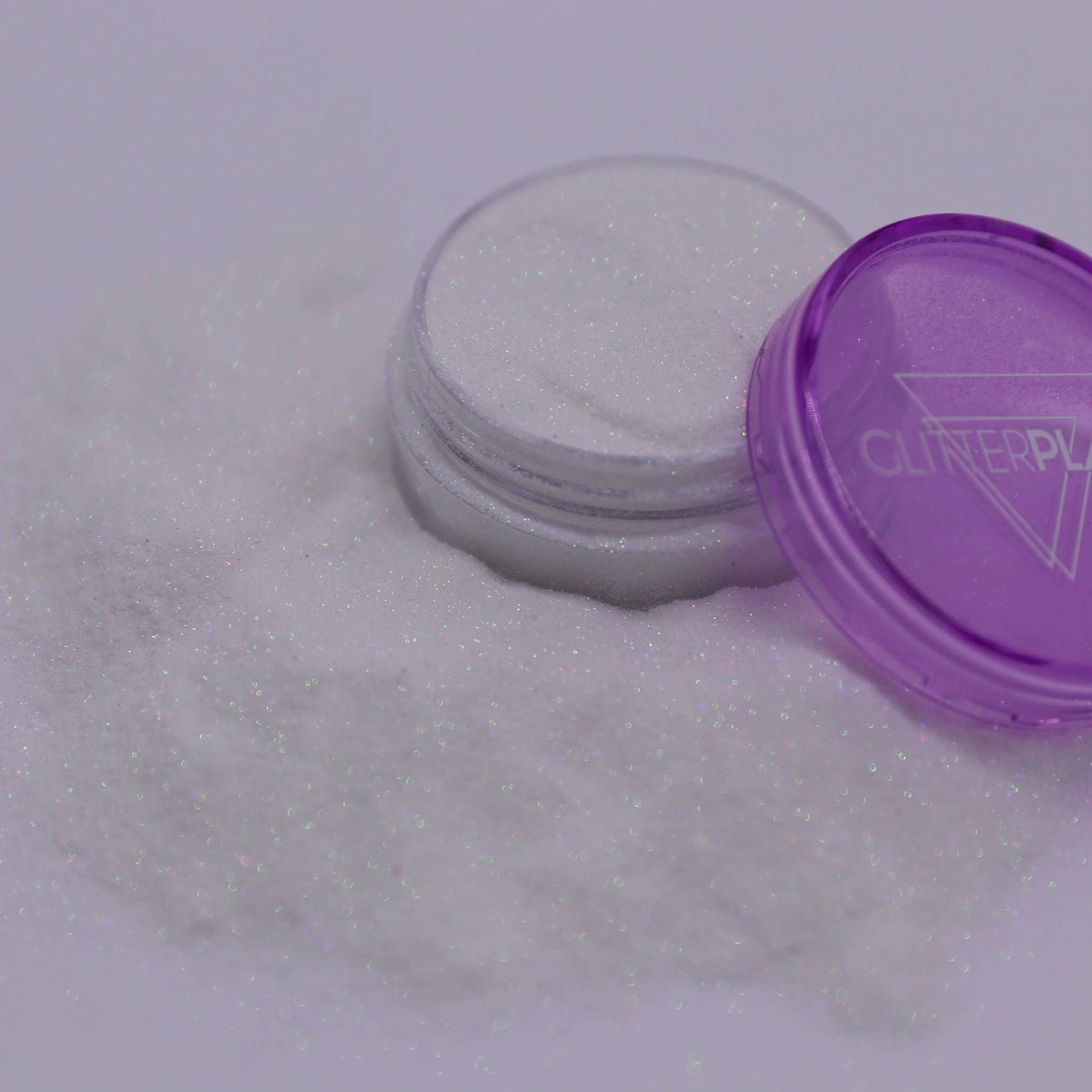 Container of glitter with a purple lid on a white background