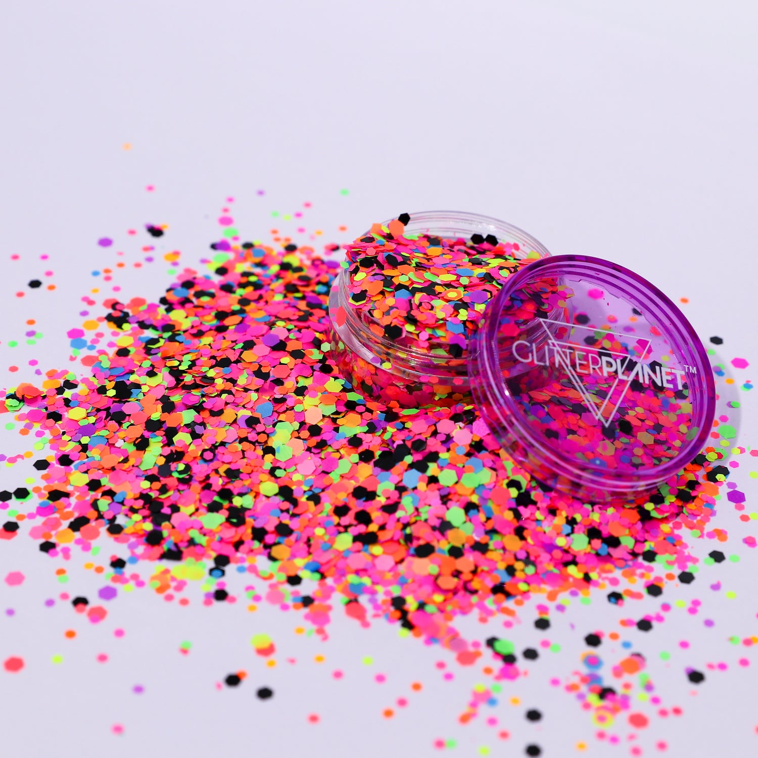 Colorful glitter scattered on a white background with a container labeled &