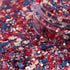 Colorful glitter with red, blue, and pink hex shapes spilling out of a container.