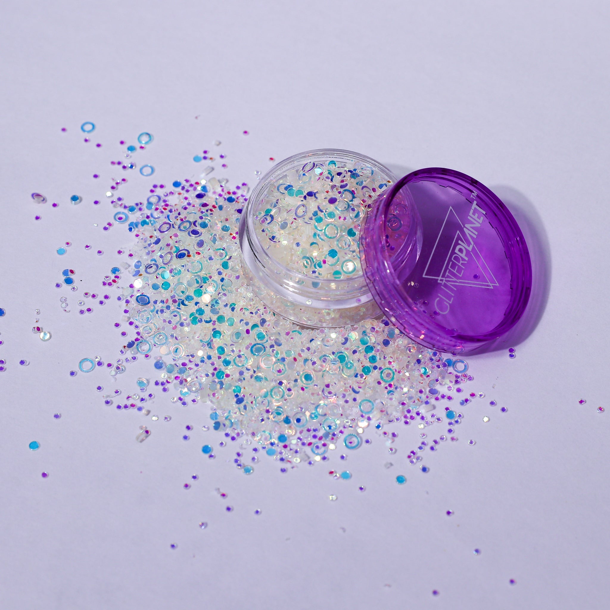 Open container of glitter with purple lid on a light purple background