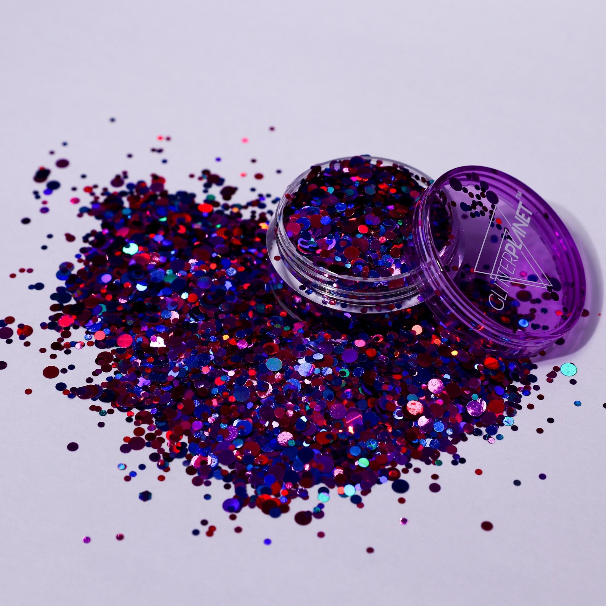 Purple glitter container with scattered glitter on a light purple background