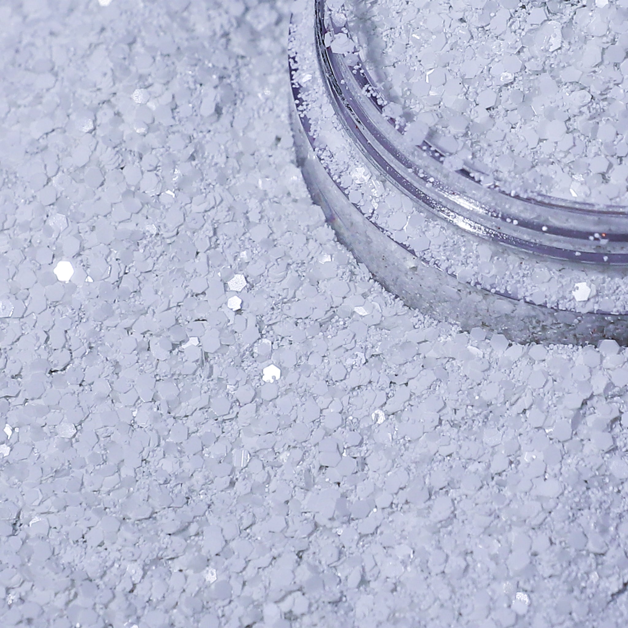 Close-up of a container of white glitter on a textured surface.