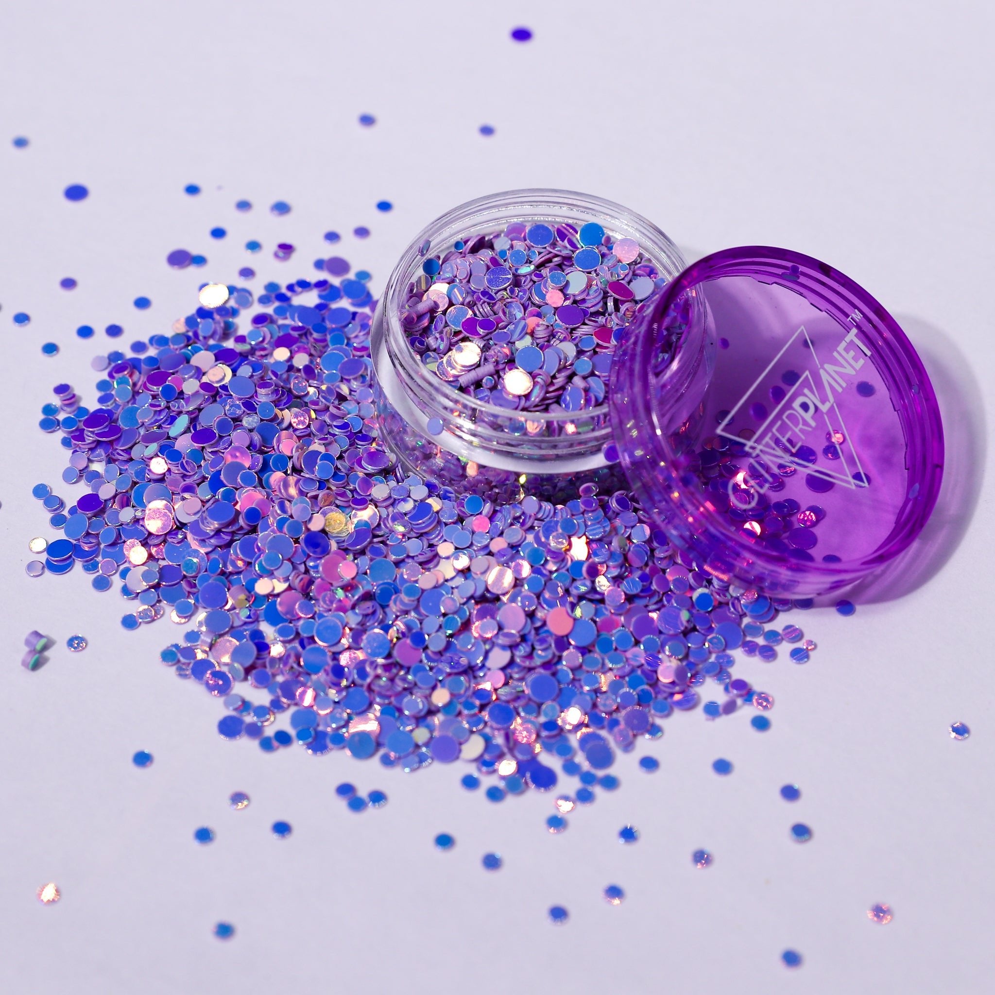 Purple glitter jar with scattered glitter on a light purple background