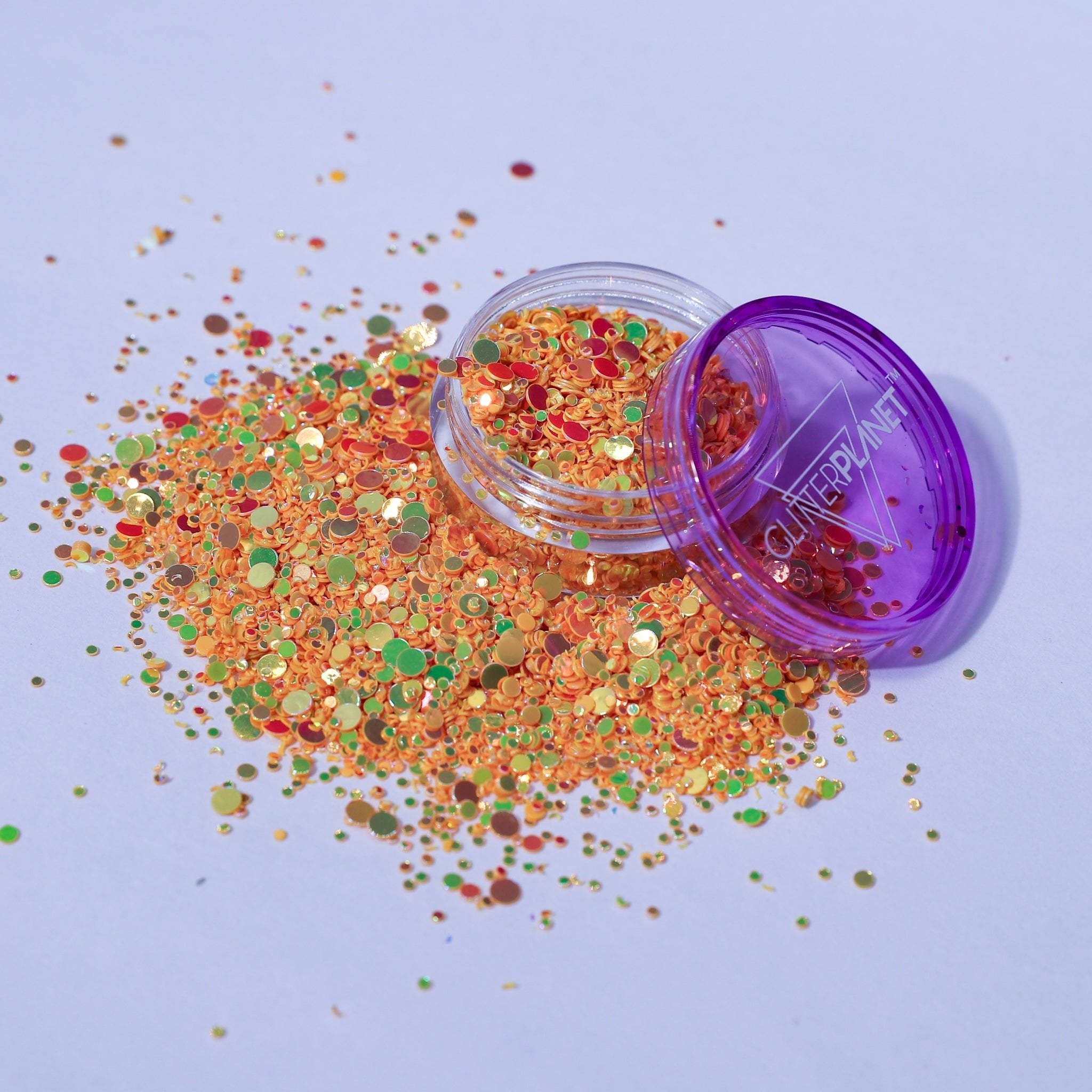 Colorful yellow iridescent glitter spilling out of a purple container labeled &