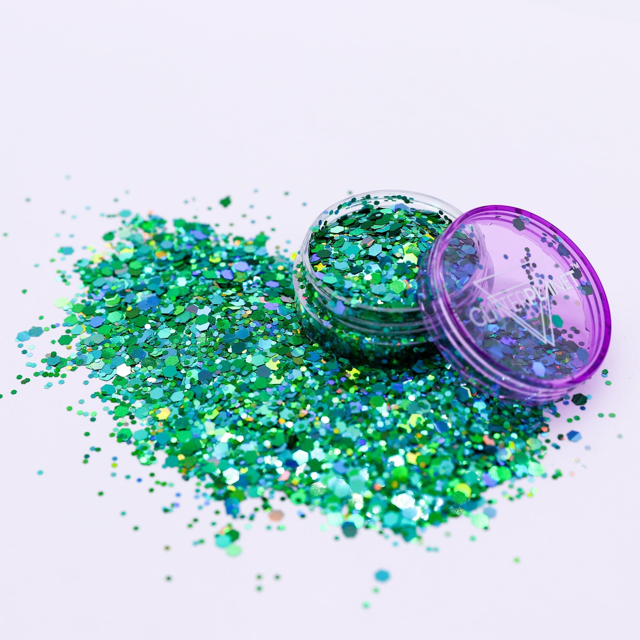 Green glitter with an open purple container on a white background