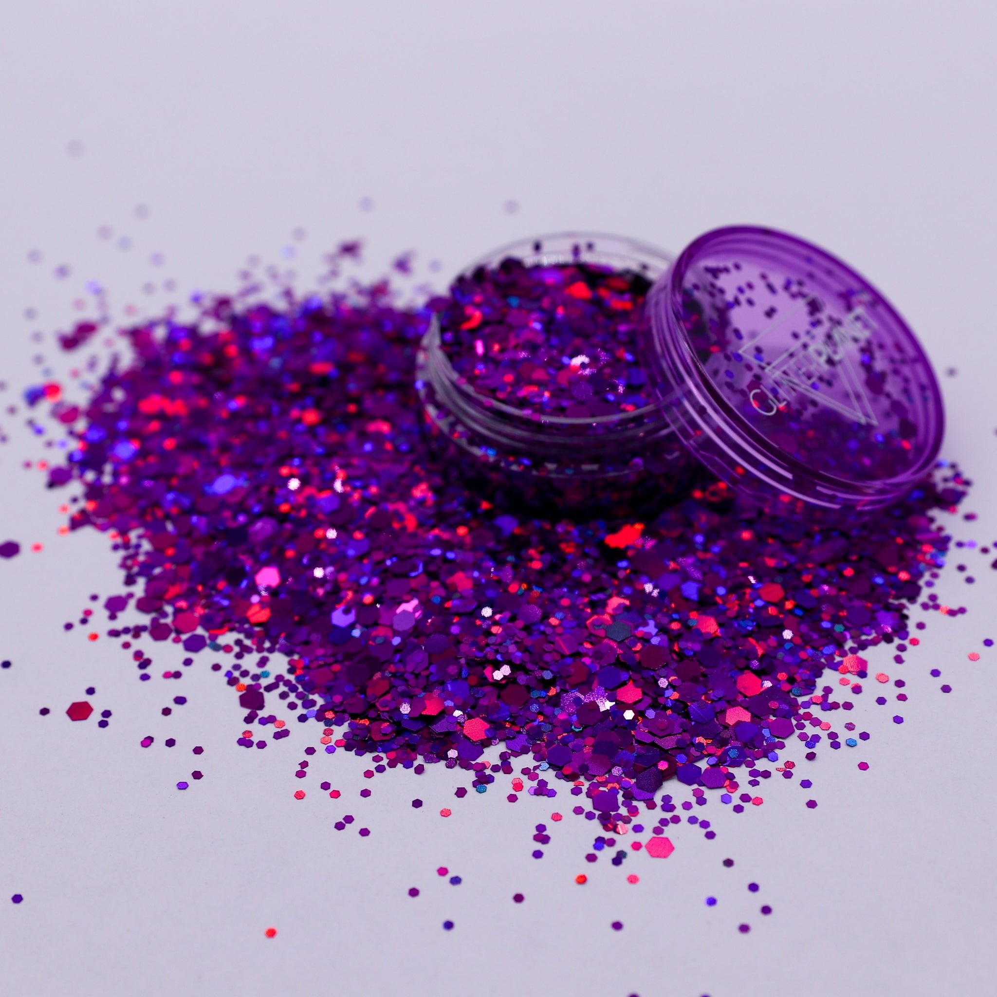 Purple glitter with an open container on a light gray background