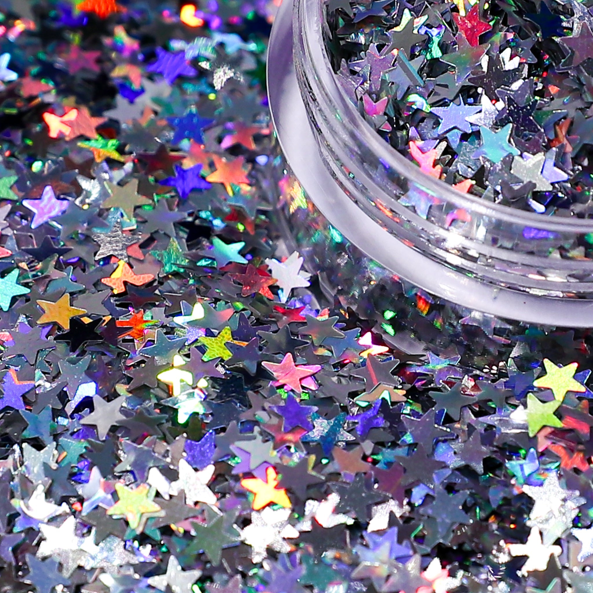 Colorful star-shaped glitter scattered on a black background with a container of glitter.