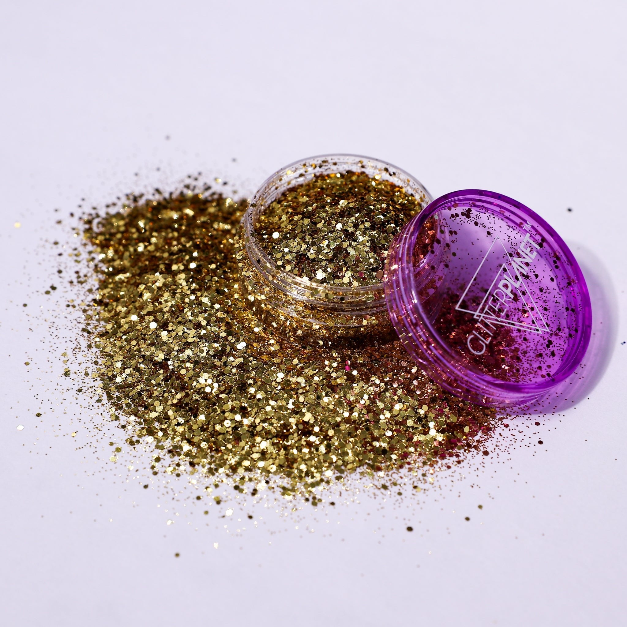 Gold glitter spilling out of a purple container with &