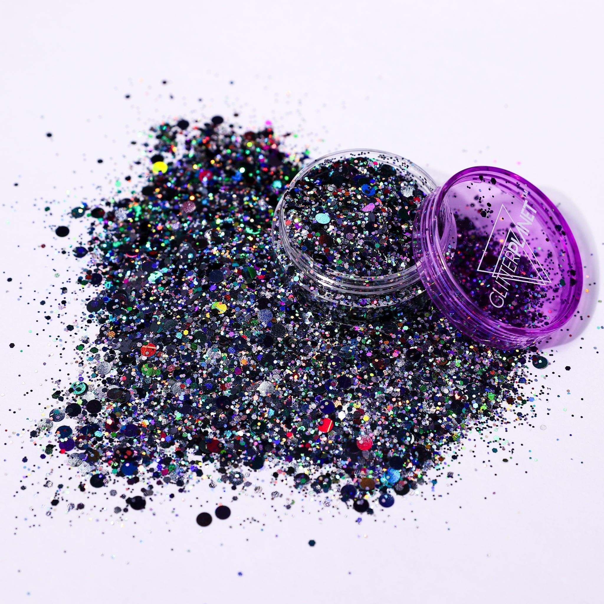 Multicolored glitter spilling out of a purple container on a white background