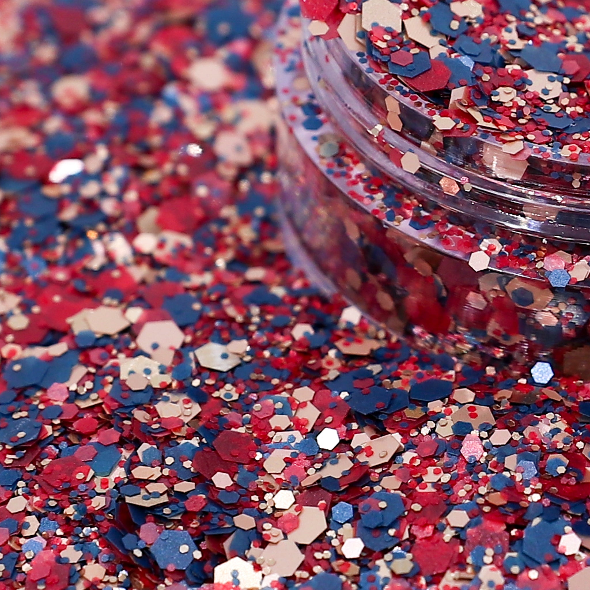 Colorful glitter with red, blue, and pink hex shapes spilling out of a container.