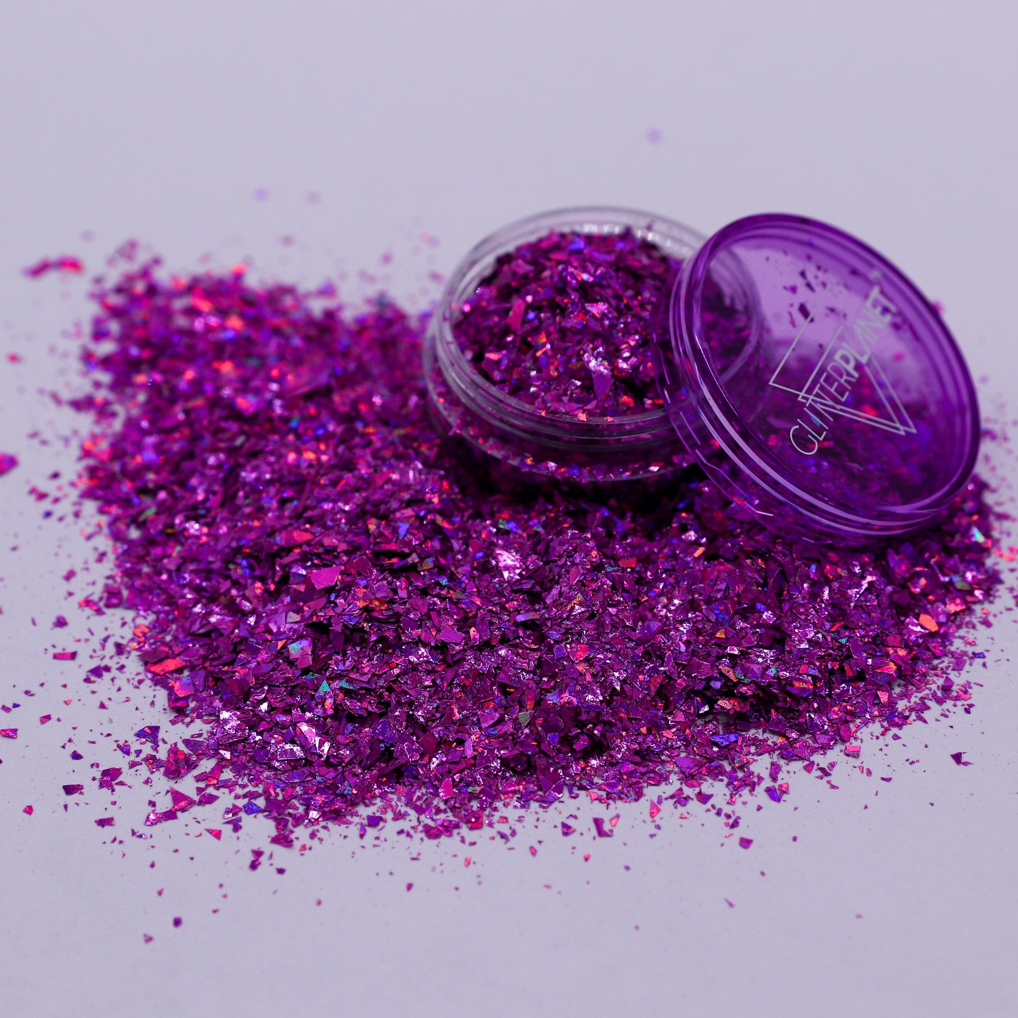 Pink glitter with an open container on a light purple background
