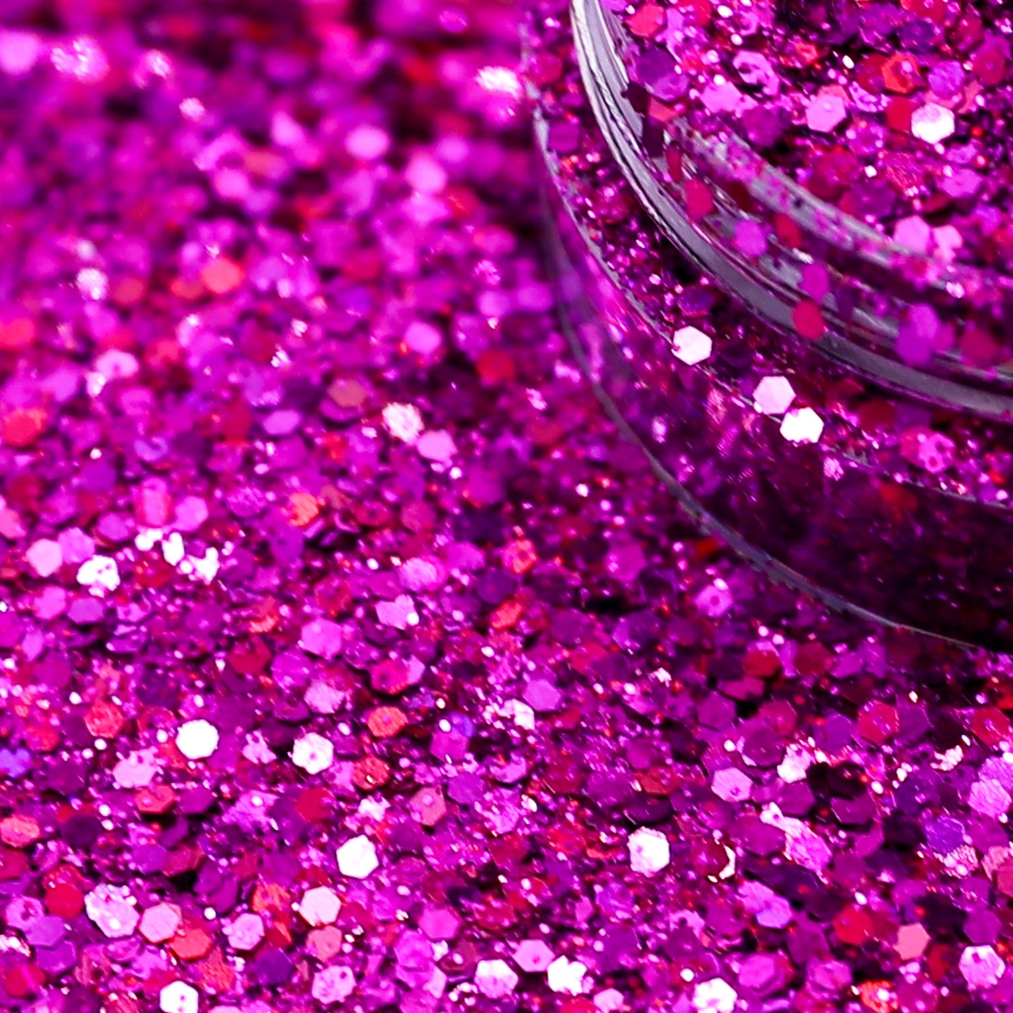 Close-up of pink glitter with a jar partially filled with glitter.
