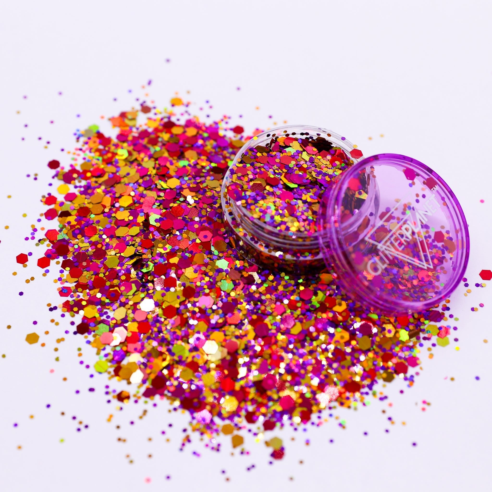 Colorful glitter spilling out of a purple container on a white background