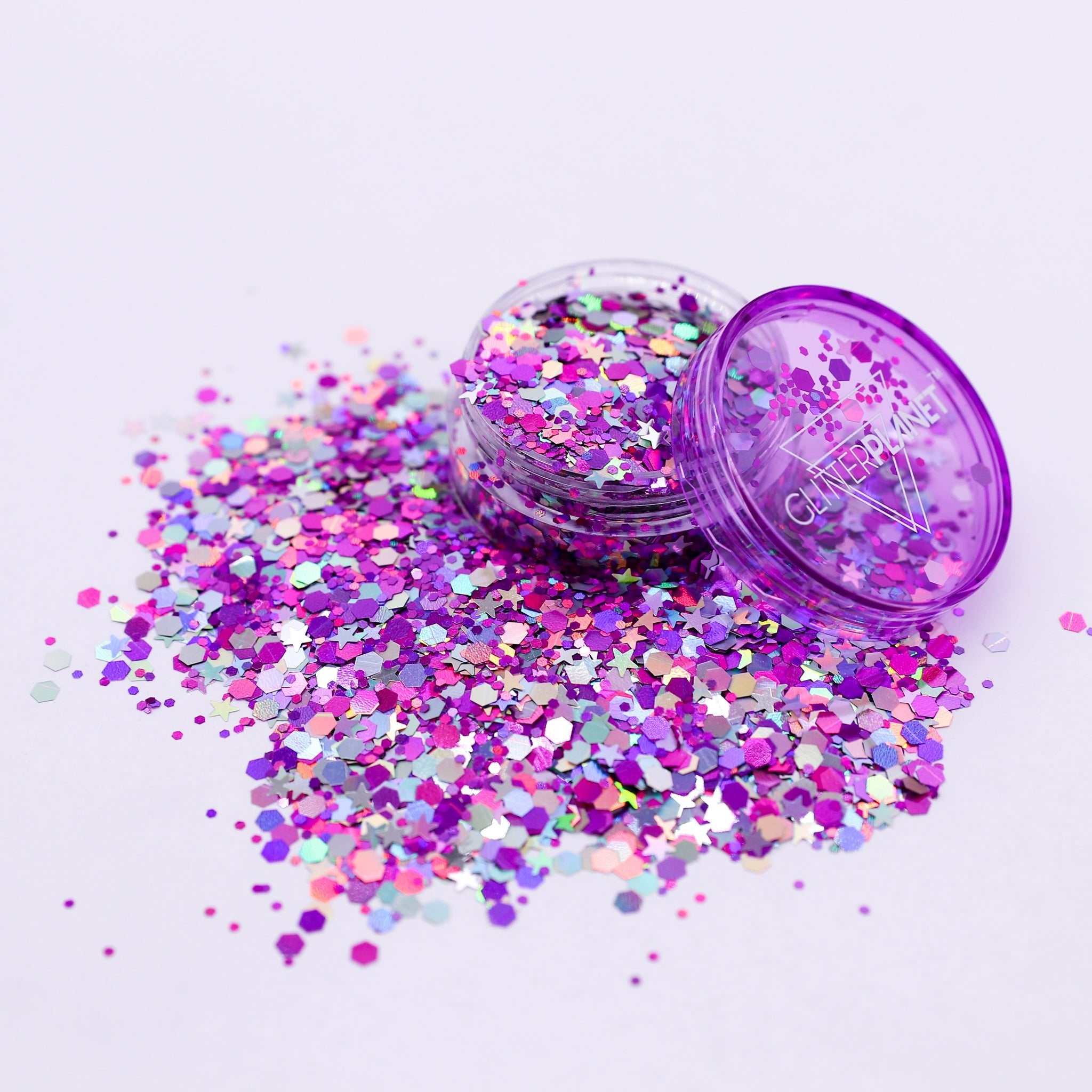 Purple glitter container with scattered glitter on a light purple background