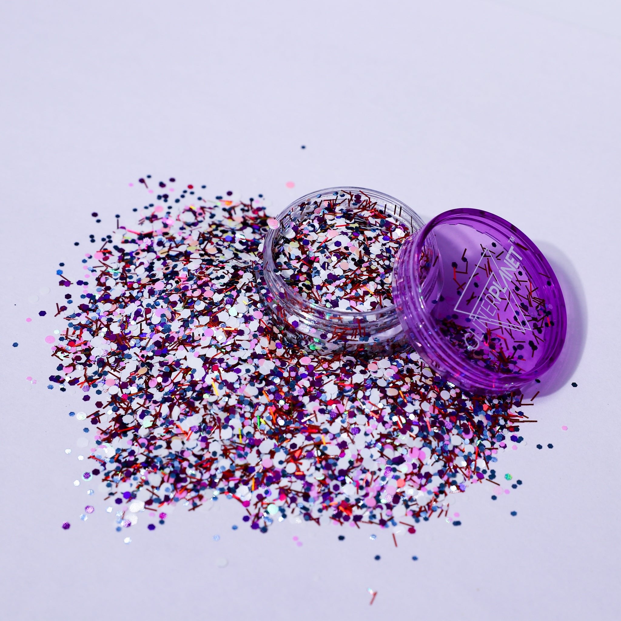 Purple glitter container with scattered glitter on a light purple background