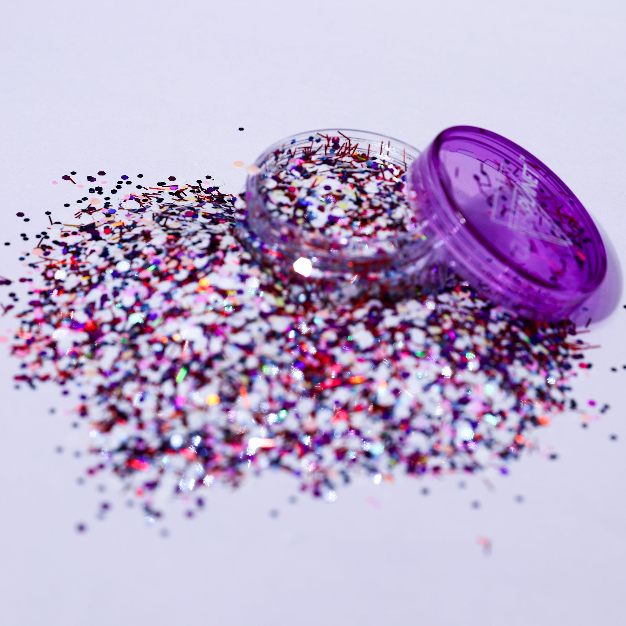 Purple glitter container with scattered glitter on a white background