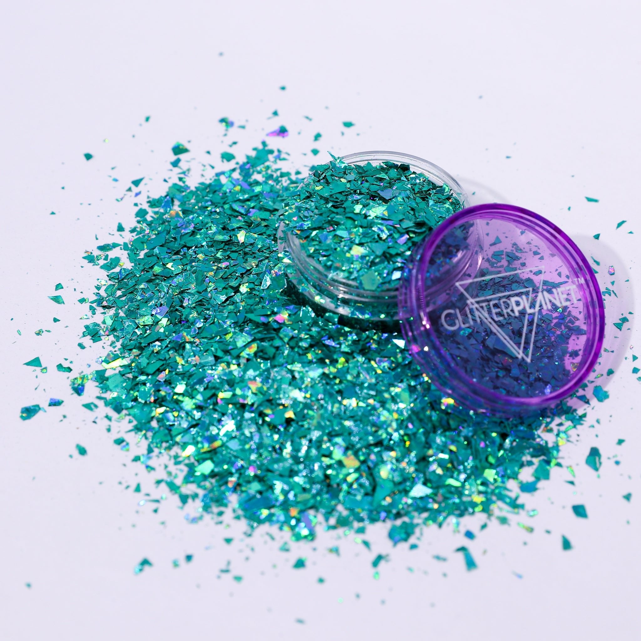 Turquoise glitter with a purple lid on a white background