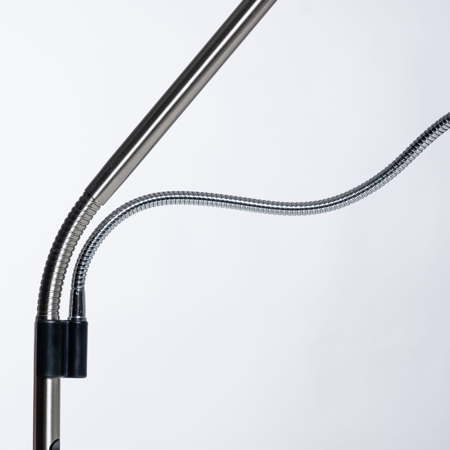Close-up of a flexible gooseneck desk lamp with a metallic silver tube and a black clamp, set against a plain white background.
