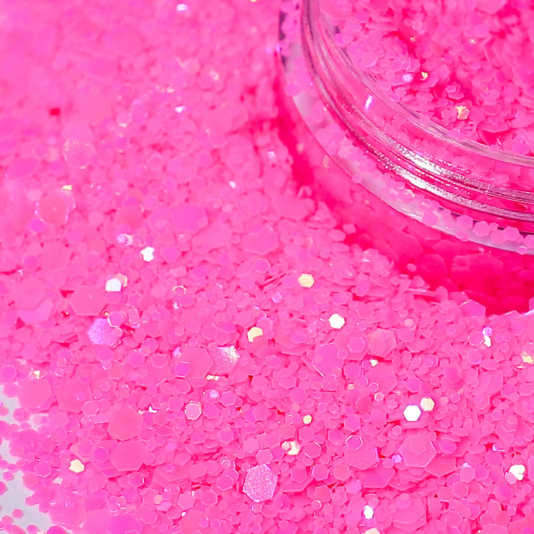 Pink glitter with a clear container partially filled with glitter on a pink background