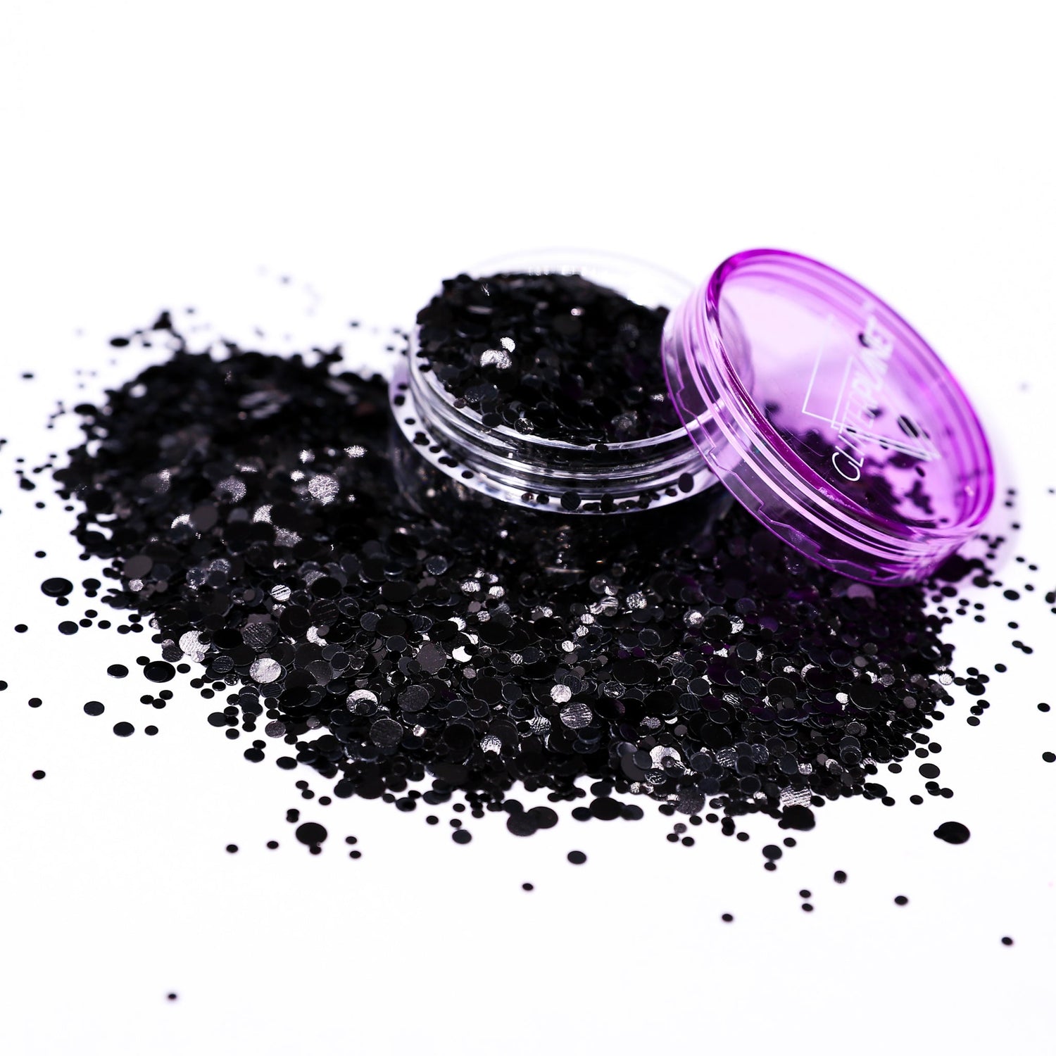 Black glitter in an open container with a purple lid on a white background