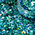 Close-up of teal glitter with a jar of glitter in the background