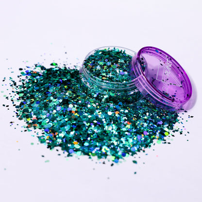 Turquoise glitter spilling out of a purple container on a white background