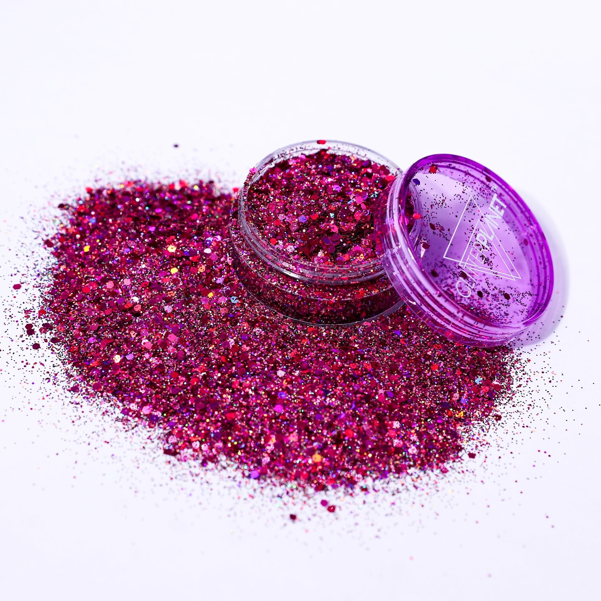 Pink glitter in an open container with a closed lid on a white background
