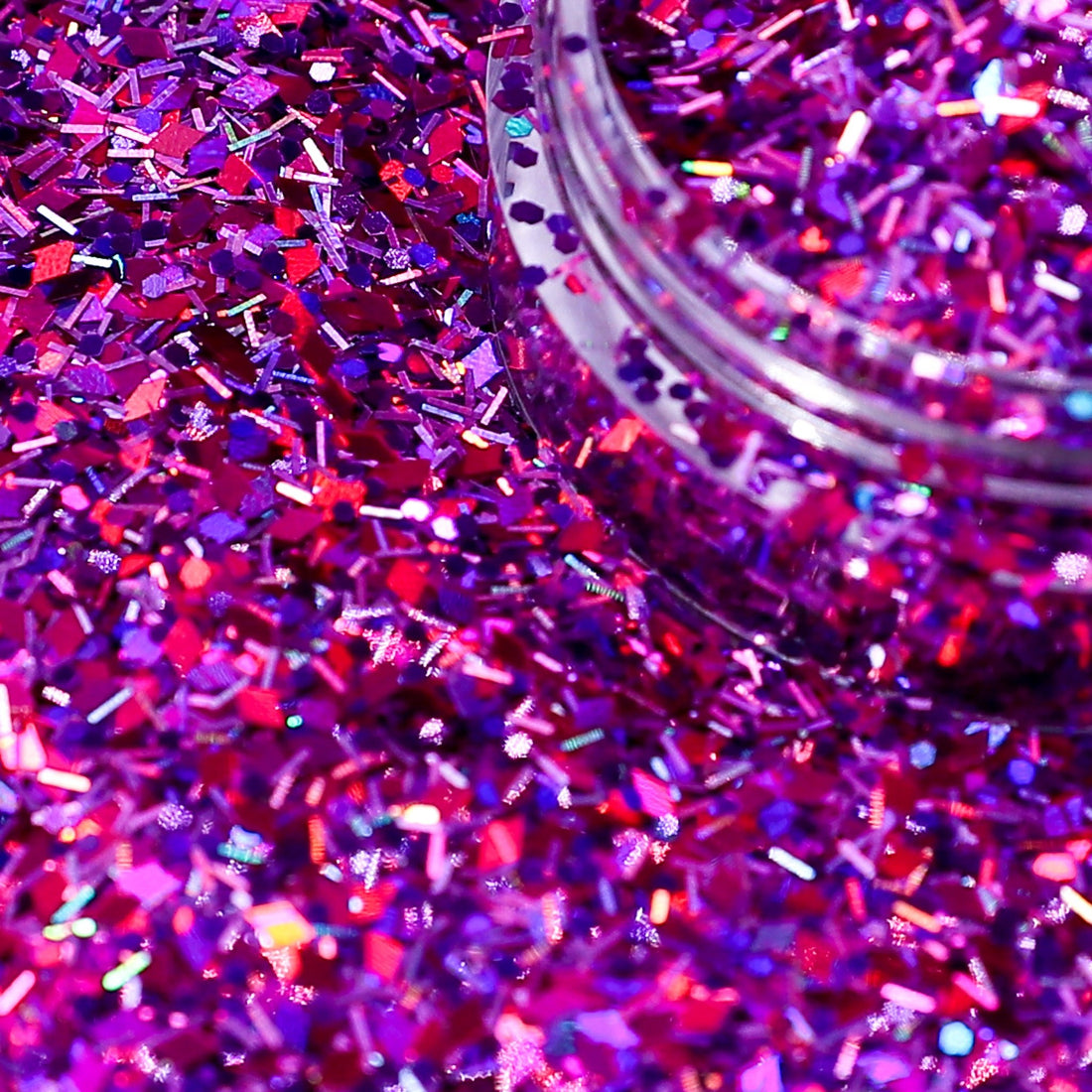 Close-up of pink and purple glitter with a jar partially filled with glitter.