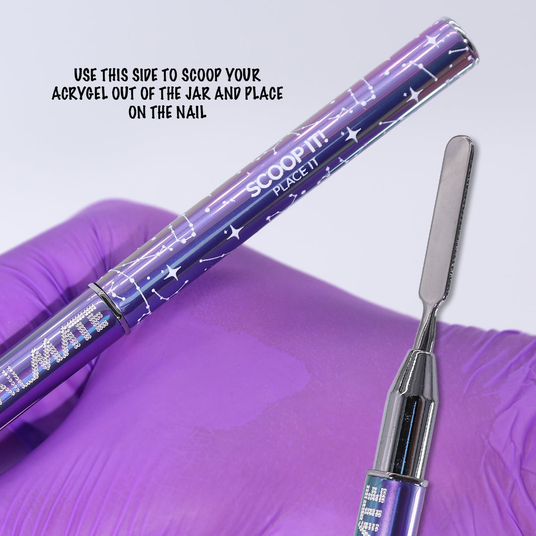 Close up of the NailMate dual ended acrygel brush showing the spatula end, used to scoop acrygel from the jar and place onto the nail, purple constellation design on purple glove background