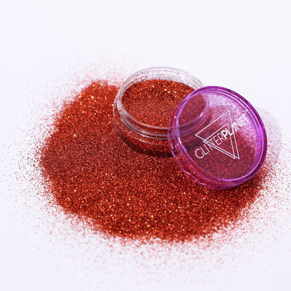 copper glitter in a small open container with a purple lid on a white background