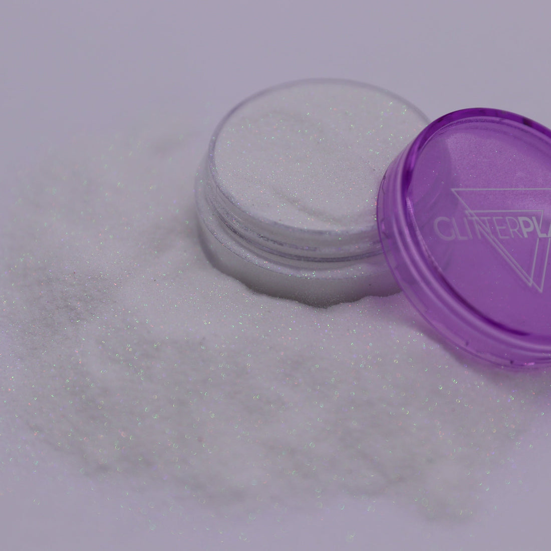 Container of glitter with a purple lid on a white background