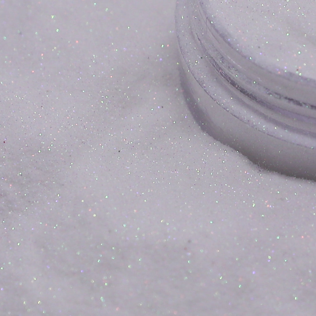 Close-up of a container of white glitter on a light gray background