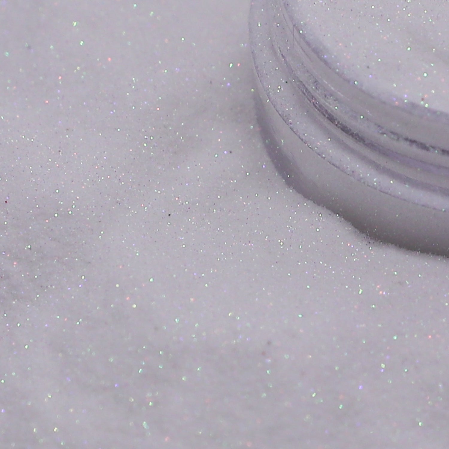 Close-up of a container of white glitter on a light gray background