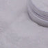 Close-up of a container of white glitter on a light gray background