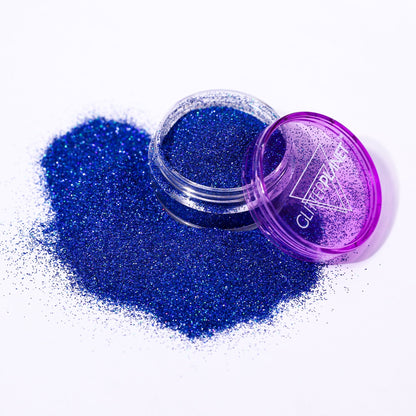 Fine holographic Blue nail glitter in a jar spilled out with the branding Glitter Planet