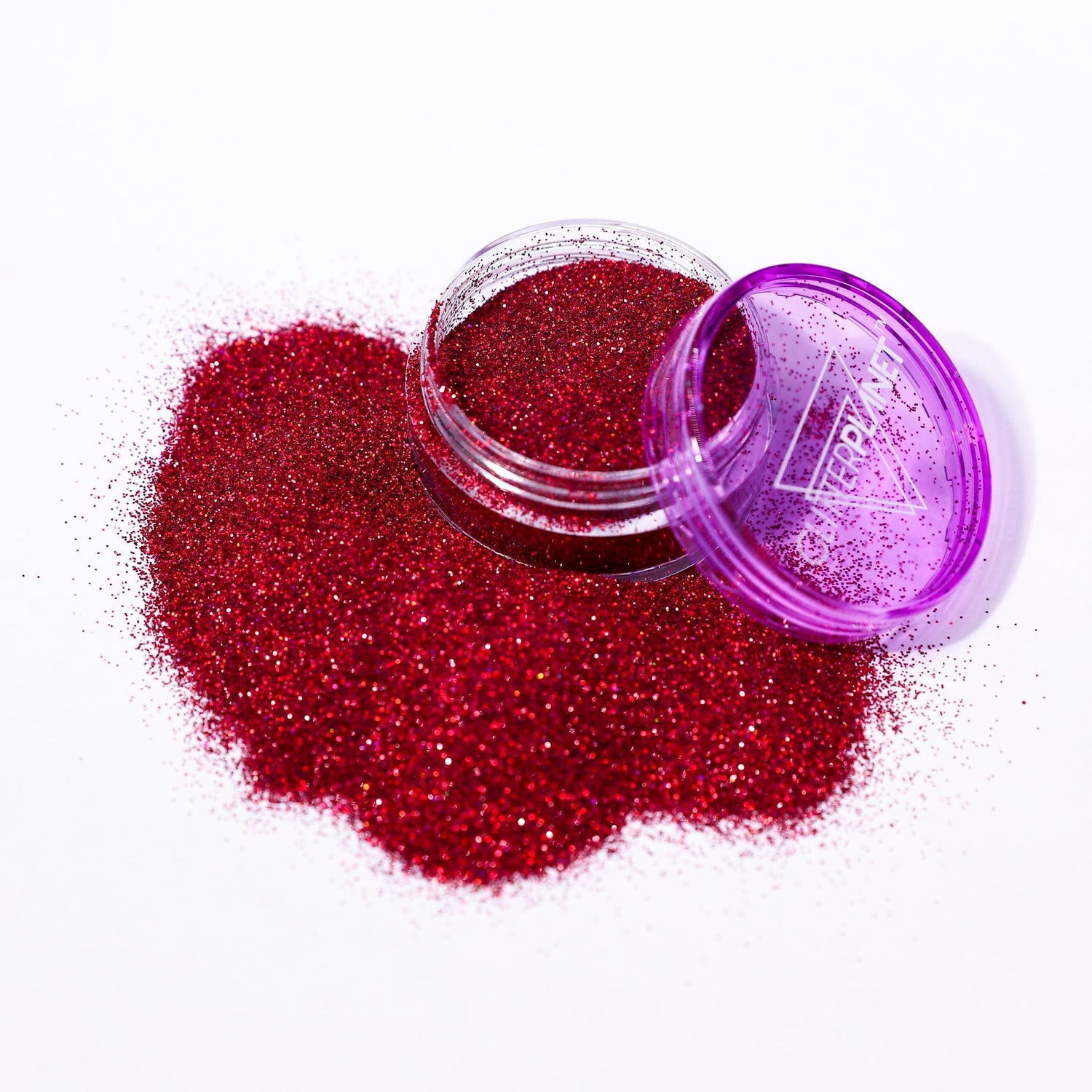 Red glitter spilling out of a purple container on a white background