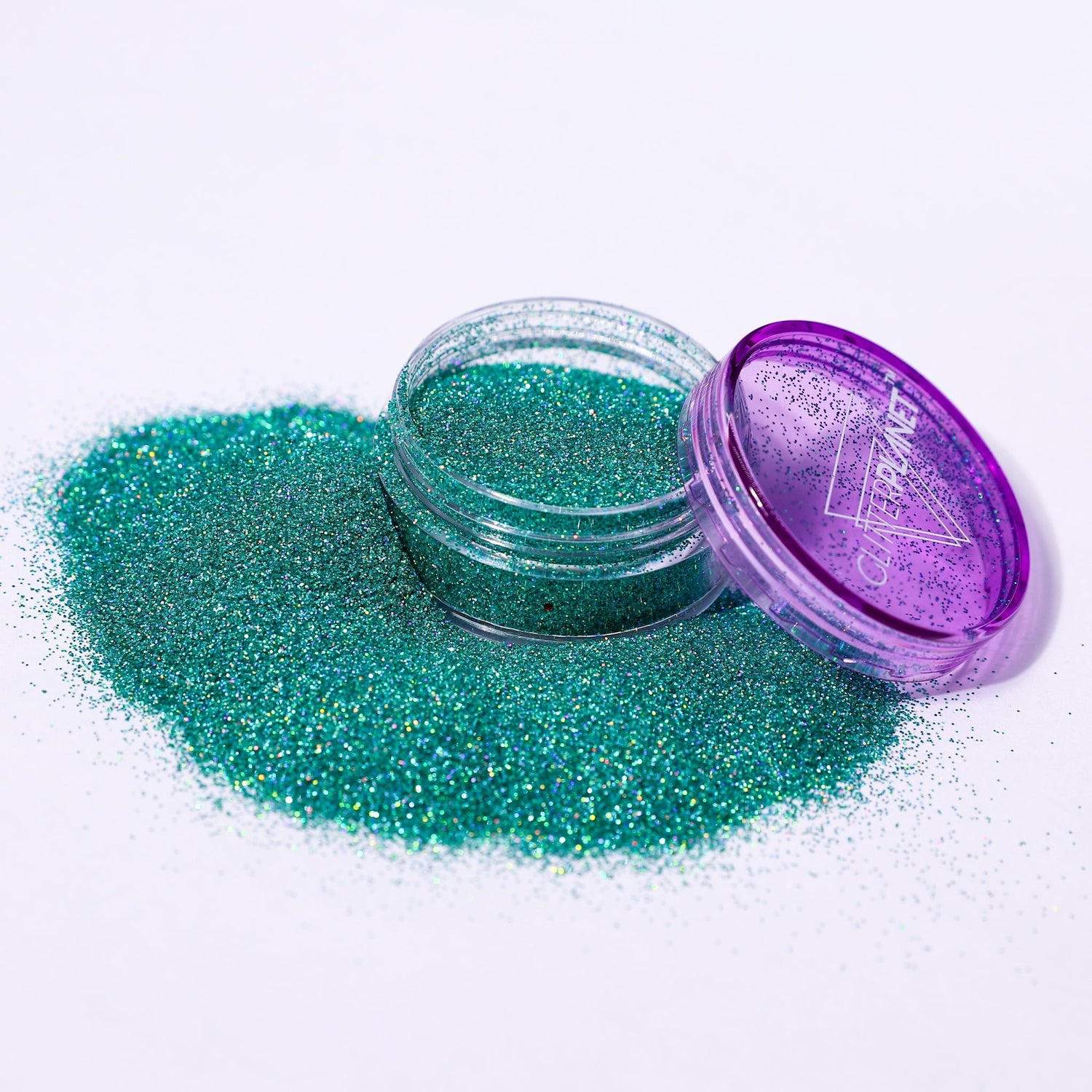 Green glitter in a small open jar with a purple lid on a white background