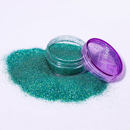 Green glitter in a small open jar with a purple lid on a white background
