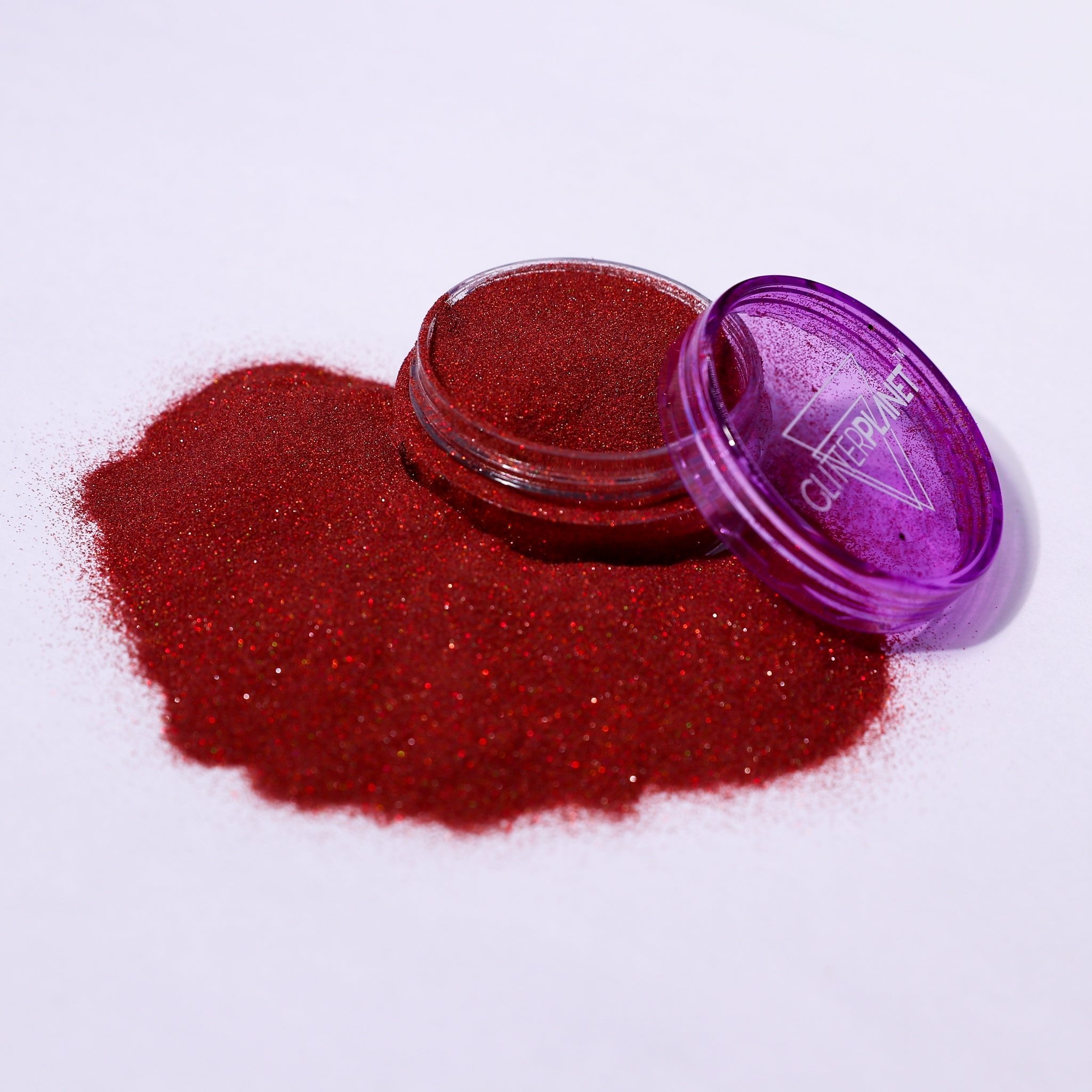 Red glitter in an open purple container on a white background