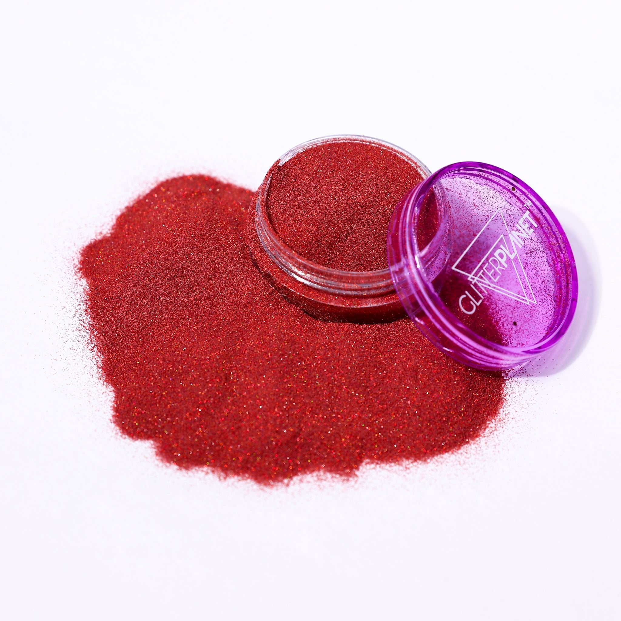 Red glitter powder spilling out of a purple container labeled &