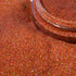 Close-up of a container of red glitter on a textured red surface