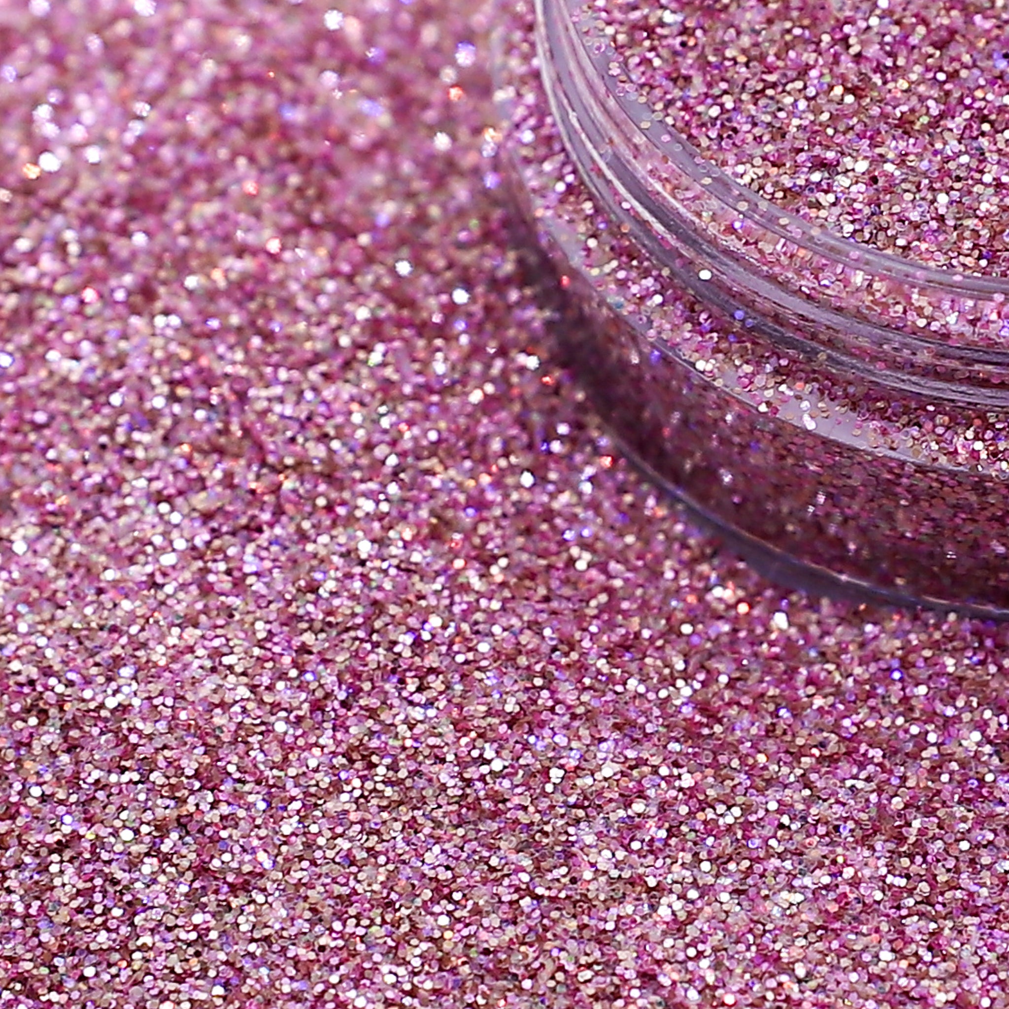 Close-up of pink glitter with a jar partially filled with glitter.