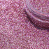 Close-up of pink glitter with a jar partially filled with glitter.