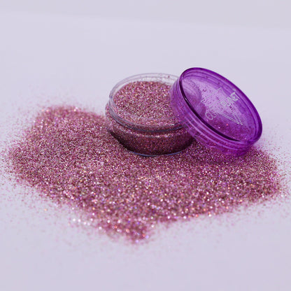 Pink glitter in an open container with a purple lid on a white background