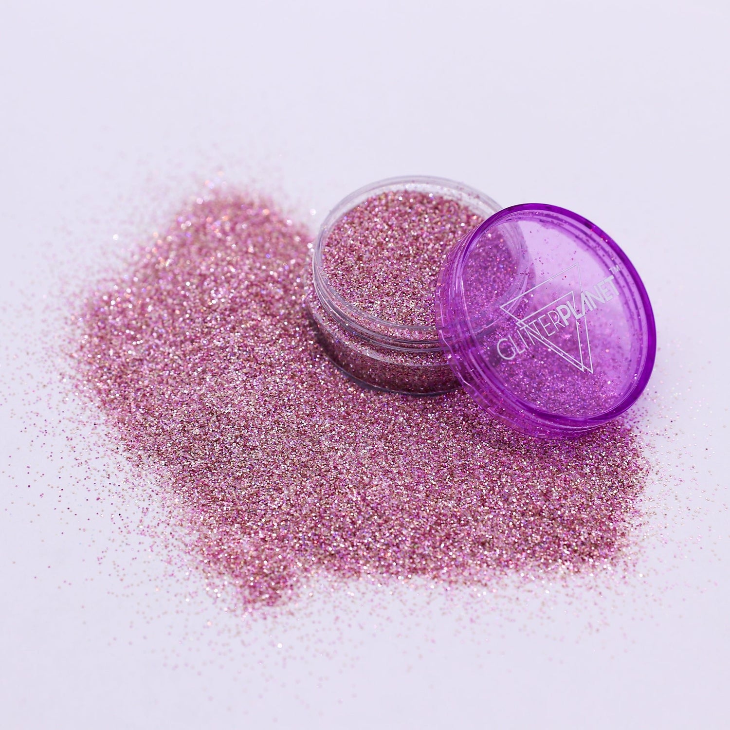 Pink glitter in an open container with a purple lid on a white background