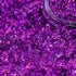 Purple glitter with a clear container partially filled with glitter.